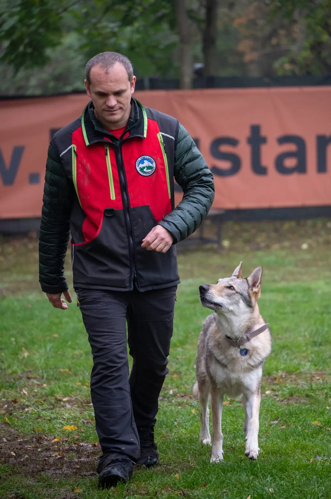 Alexandru Cănăvoiu, instructor de mantrailing, mergând pe iarbă alături de câinele lui